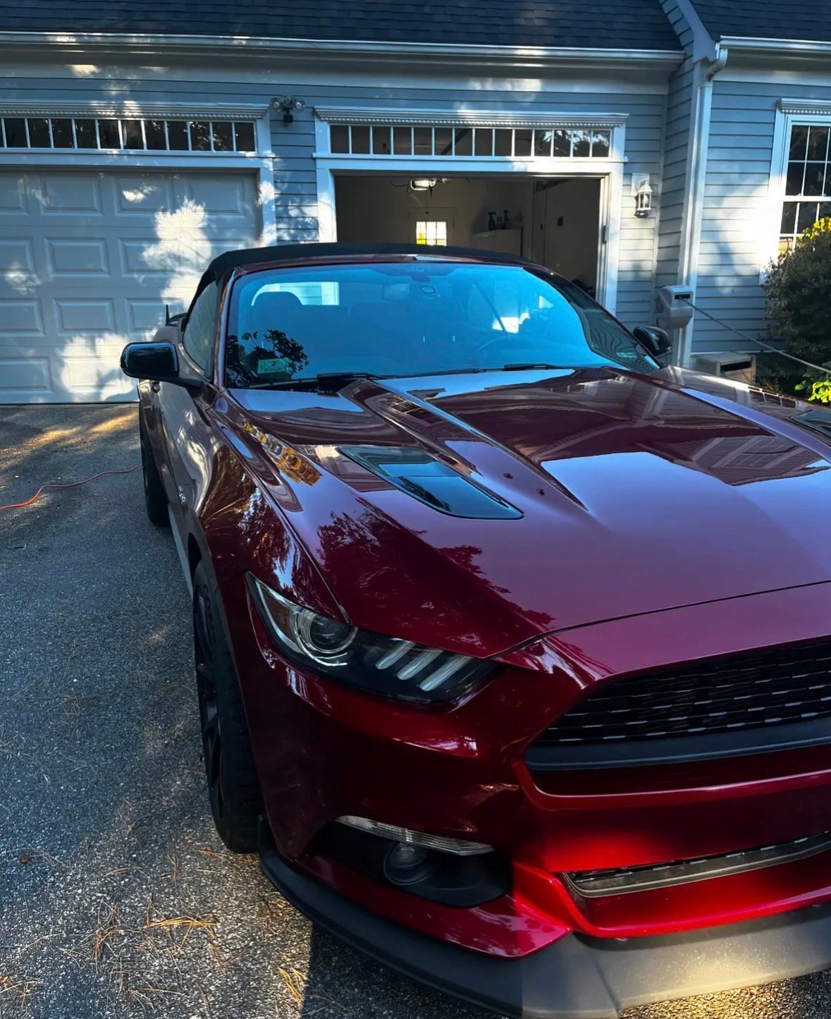 Red Ford Mustang parked in driveway in front of garage with tinted windows